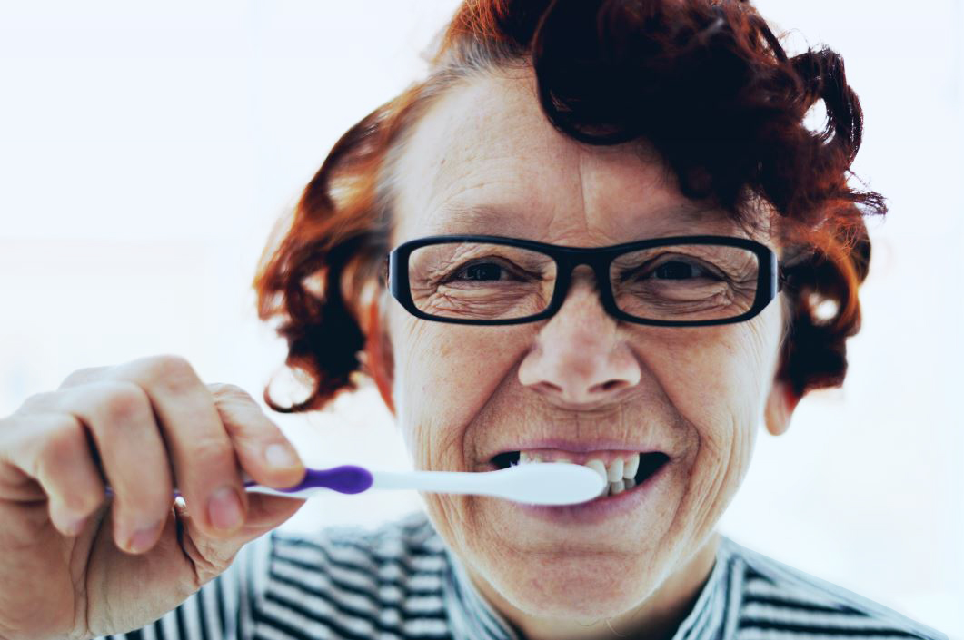 Glad kvinna som borstar tänderna